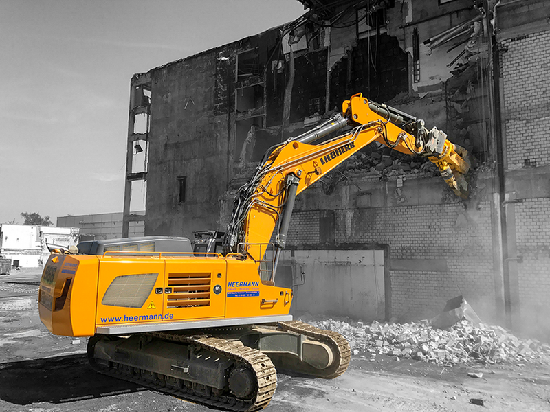 Ein Bagger reisst auf einer Baustelle die Wand ein